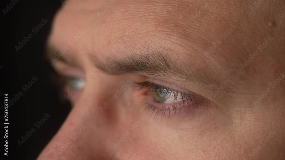 Man eyes with blinking eyelids. Close up male face with natural skin on black background. Male looking into distance, eyebrows, eyelashes, skin issues macro view Man eyes with blinking eyelids. Close up male face with natural skin on black background. Male looking into distance, eyebrows, eyelashes, skin issues macro view