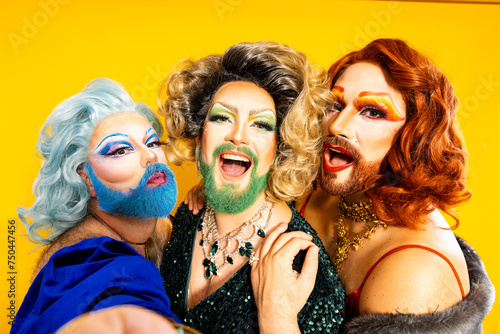POV of three cheerful drag queens taking a selfie against yellow background photo
