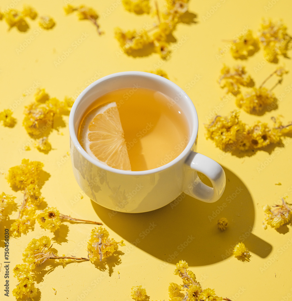 Herbal tea with immortelle and lemon in a white cup on a yellow background close up. Herbal tea with immortelle and lemon in a white cup on a yellow background close up.