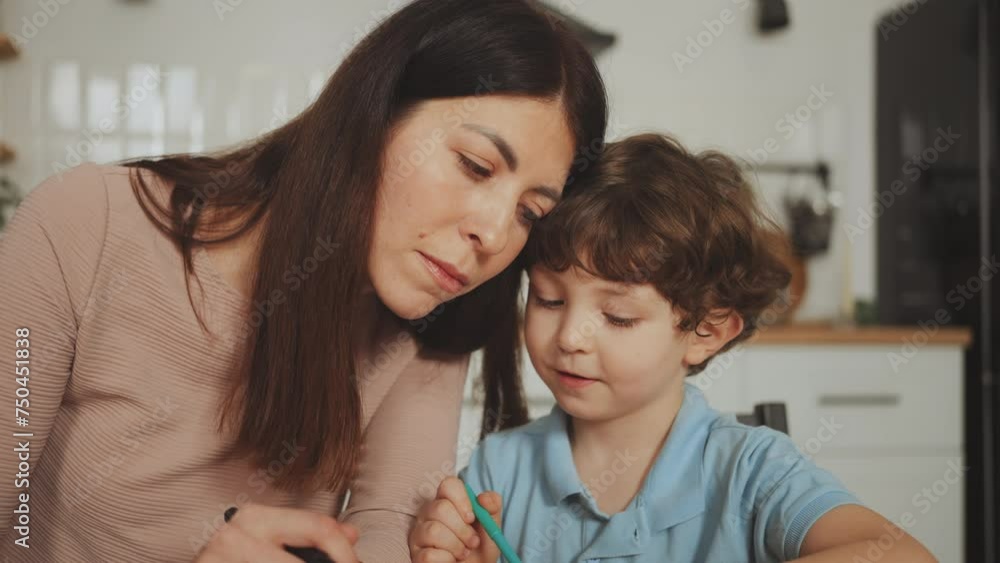 Mother attentively assists her young son with creative task at home, moment of family bonding. Tender moment of attentive parenting at home Mother attentively assists her young son with creative task at home, moment of family bonding. Tender moment of attentive parenting at home