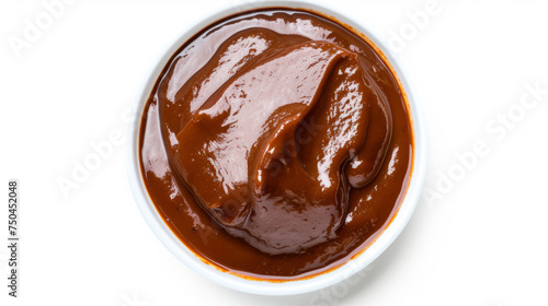 Top-down view of smooth mole sauce in a white bowl with orange trim isolated on a white background. Mexican cuisine concept for culinary arts and menu design photo