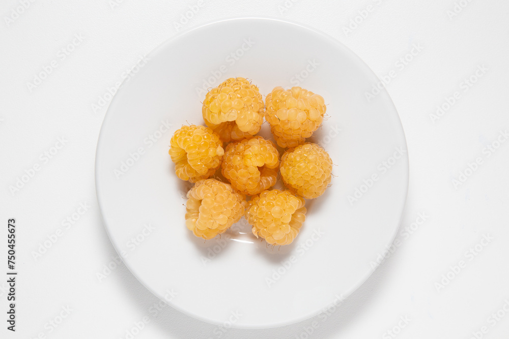 raspberries yellow group on a white plate raspberries yellow group on a white plate