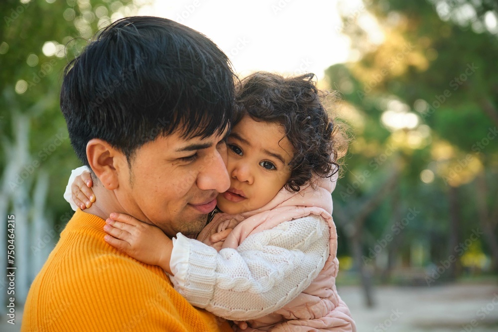 Portrait of happy Ecuadorian one year old daughter hugging her father in a park. Portrait of happy Ecuadorian one year old daughter hugging her father in a park.