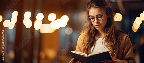Serious Young Woman Engrossed in Studying with Open Textbook in University Library photo