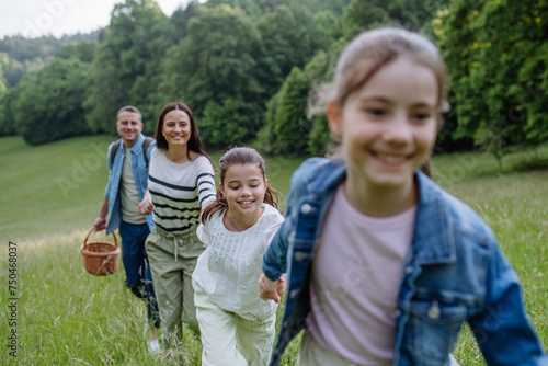 Family on walk in forest, going through meadow. Picking mushrooms, herbs, flowers picking in basket, foraging. Concept of family ecological hobby in nature.