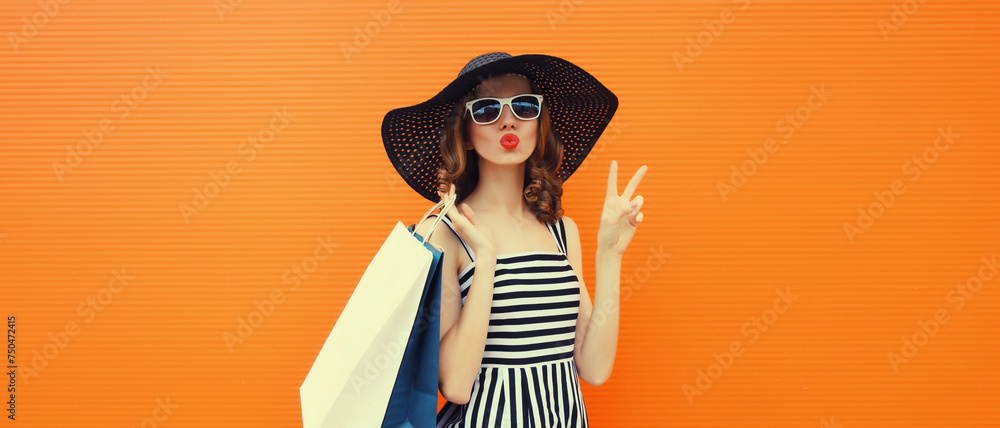 © rohappy - Beautiful happy woman model with shopping bags in summer black hat, dress on orange background © rohappy - Beautiful happy woman model with shopping bags in summer black hat, dress on orange background