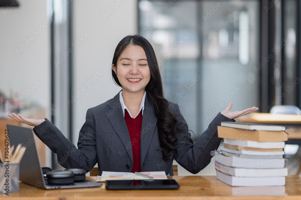 Happy young asian woman wearing earphones and using laptop computer at desk in office, Female student with stack of books and laptop. Happy young asian woman wearing earphones and using laptop computer at desk in office, Female student with stack of books and laptop.