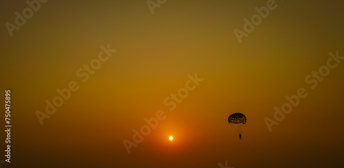 Parasailing extreme sports on beach in sunset background. Paragliding in front of an amazing sunset. A beautiful background of a parasailing parachute on the backdrop a sunset on an evening sky.