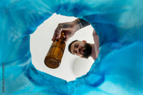 Man throwing glass bottle into recycling bin. Empty alcohol bottle, throwing, New Year's resolutions, drink less alcohol healthy lifestyle without alcoholic drinks.