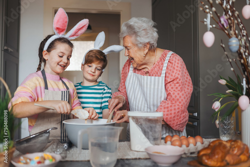 Grandmother with grandchildren preparing traditional easter meals, baking cakes and sweets. Passing down family recipes, custom and stories. photo