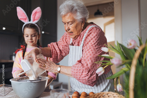 Grandmother with granddaughter preparing traditional easter meals, baking cakes and sweets. Passing down family recipes, custom and stories. photo