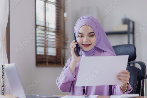 Asian islamic women working planning and data analysis financial with smartphone and laptop at office desk, Business accounting and marketing online concept.