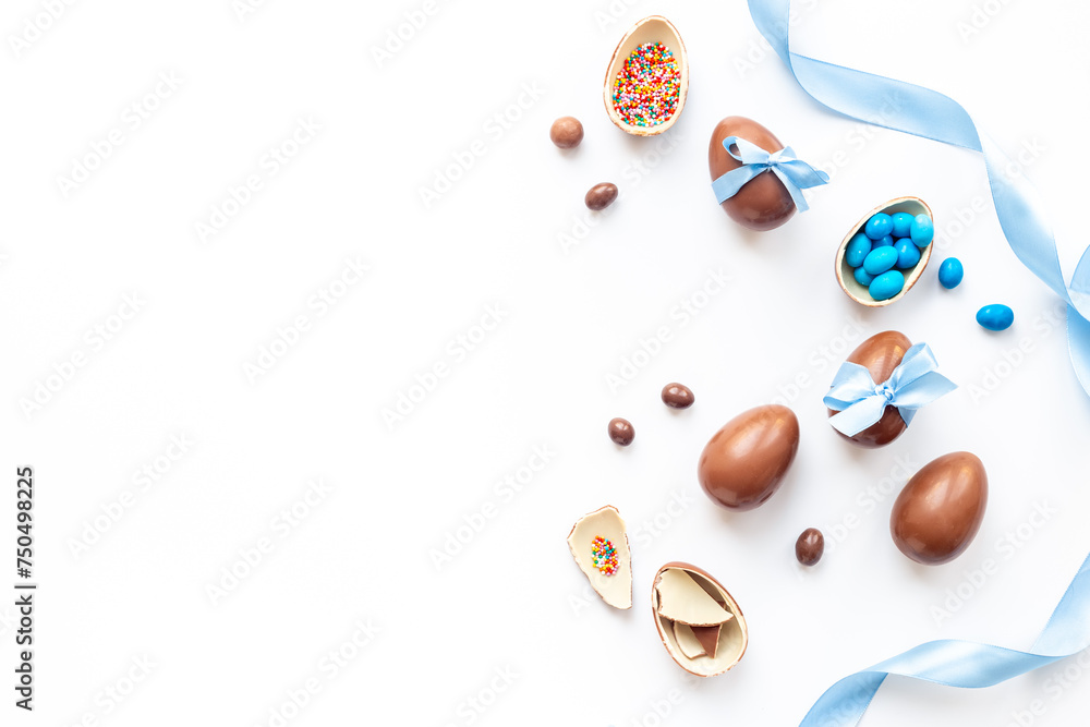 Easter festive background. Chocolate Easter eggs in blue ribbon with sweets Easter festive background. Chocolate Easter eggs in blue ribbon with sweets