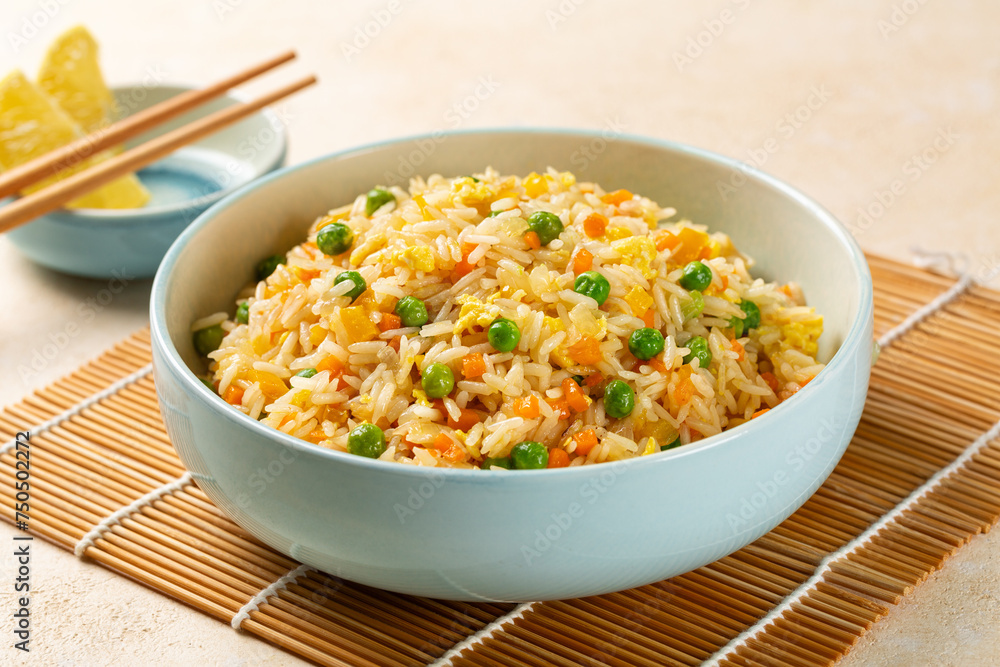 Fried rice with egg and vegetables, onion, bell pepper, carrot, green peas. Prepared and served in a light blue plate, chopsticks. Fried rice with egg and vegetables, onion, bell pepper, carrot, green peas. Prepared and served in a light blue plate, chopsticks.