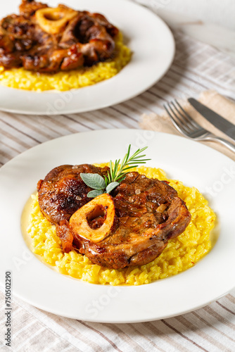Ossobuco meat, specialty of Lombard cuisine of cross-cut beef shanks braised with onion, white wine, and broth. Served with risotto alla milanese, rise made with saffron. Italian dish. Vertical.