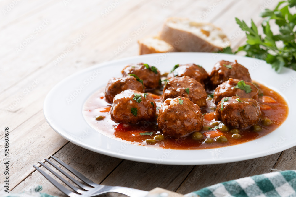 Meatballs, green peas and carrot with tomato sauce on wooden table