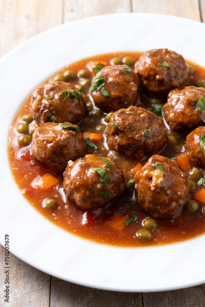Meatballs, green peas and carrot with tomato sauce on wooden table. Close up Meatballs, green peas and carrot with tomato sauce on wooden table. Close up