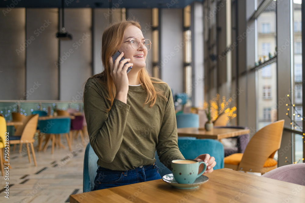 Blonde beautiful stylish caucasian woman in casual outfit sitting at the cafe talking on her phone. High quality photo