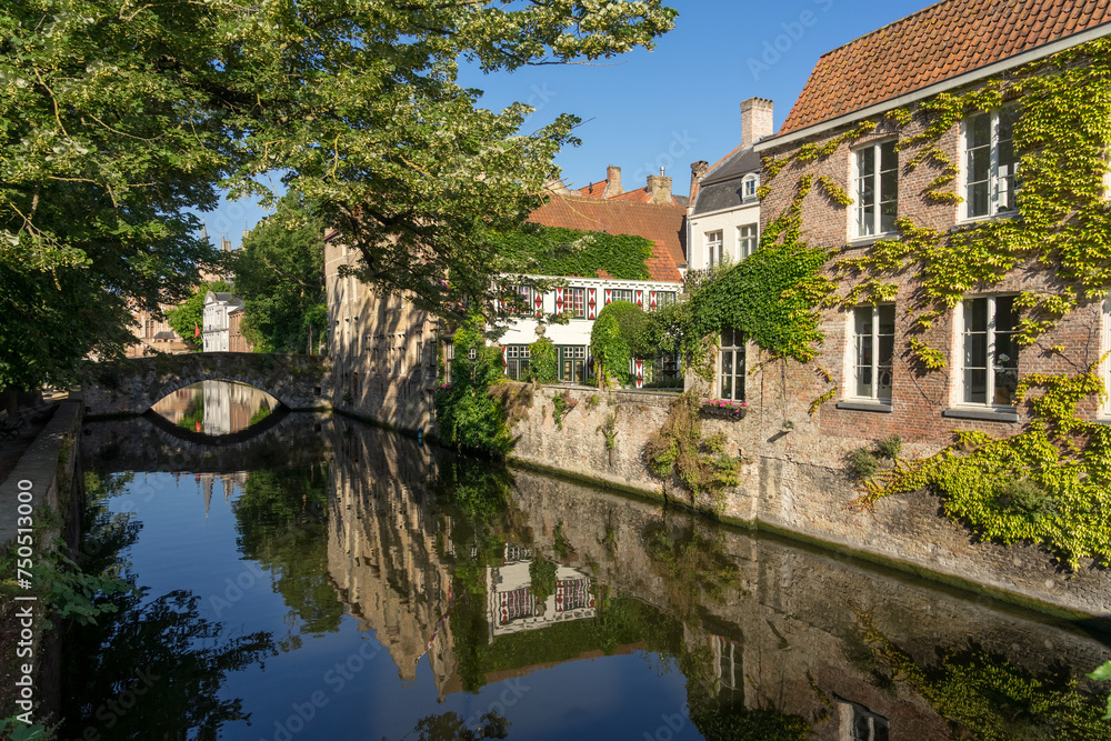 Meestrat bridge and historic buildings reflected on the canal in the old town of the beautiful city of Bruges in Belgium in a sunny day.