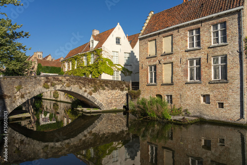 Peerden bridge and historic buildings reflected on the canal in the old town of the beautiful city of Brugge in Belgium in a sunny day.