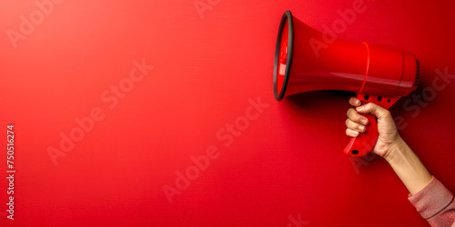 Red megaphone in woman hand on a red background, copy space, hiring, advertising, announce, banner concept