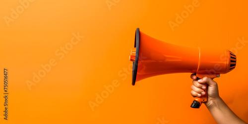 Orange megaphone in woman hand on a orange background, copy space, hiring, advertising, announce, banner concept photo