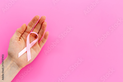 Pink ribbon symbol of breast cancer with hands. Medical support and prevention