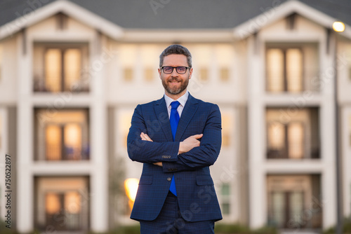 Business deal. Real estate agent in suit. Business man in suit near new house. Man broker or real estate agent. Job offer, Purchase offer. Discount offer. Business deal.