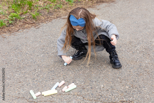 Little girl drawing with chalk on asphalt on spring. Creative development of children