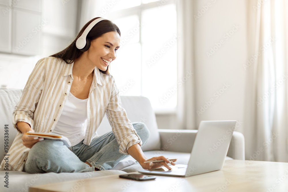 Obraz premium Online Education. Smiling Woman In Wireless Headphones Studying With Laptop At Home