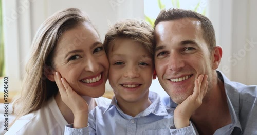 Close up faces of cute little boy touch cheeks of loving mother and father, smiling, looking at camera, having perfect teeth and attractive appearance, advertising dental services, showing family ties photo