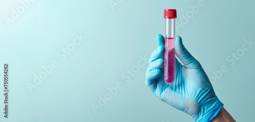 The simplicity of a blood vial in a clinical glove contrasts with the plain blue backdrop, signifying cleanliness