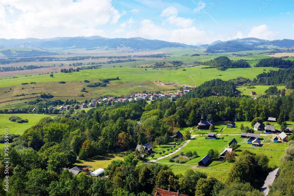 picturesque landscape of the rural valley and farmland scenery of slovakia. village on the hill and mountains in the distance, view from above. bright sunny weather in summer