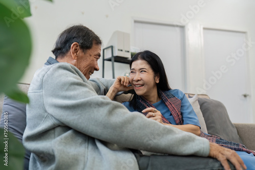 Older couples sit and chat and head over each other relaxed and happy on sofa at home on weekday in comfortable photo