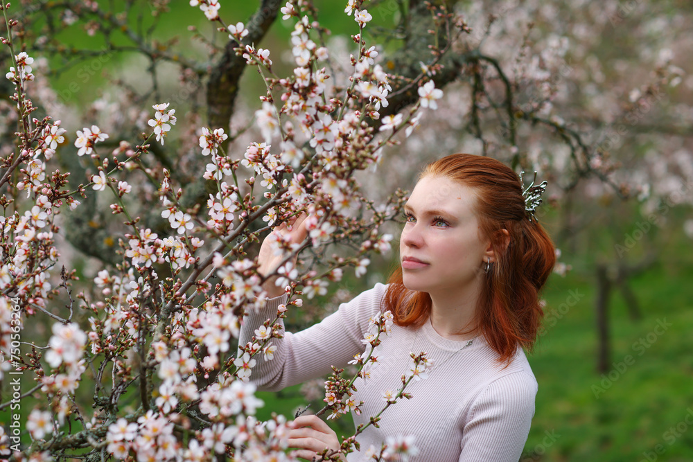 Spring Beautiful romantic red haired girl standing in blooming garden. Spring Beautiful romantic red haired girl standing in blooming garden.