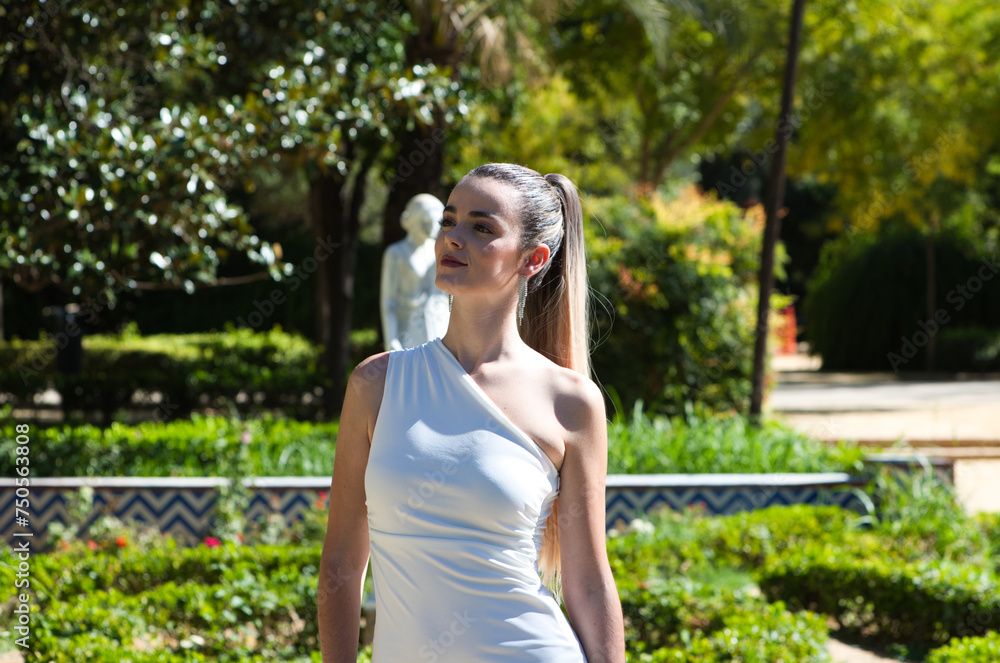 Young and beautiful woman with long blond hair and a short white dress is in a famous park in seville rich in vegetation, spain. Travel and holiday concept. Young and beautiful woman with long blond hair and a short white dress is in a famous park in seville rich in vegetation, spain. Travel and holiday concept.