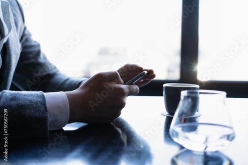 Man using a cell phone on cafe terrace, news paper and coffee photo