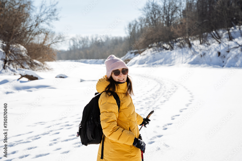 Woman in glasses in nature on the background of snow, smiling, man with backpack traveling on snowy river.