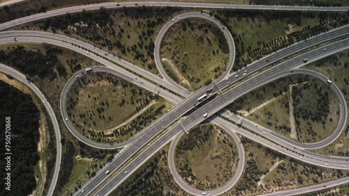 Engineering meets nature in this aerial view of a highway intersection surrounded by trees. The roads pattern cuts through the landscape, with grass and nonbuilding structures dotted throughout photo