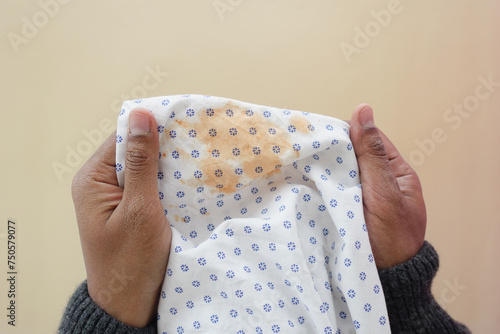  men holding white dirty bed cover, showing making stain photo