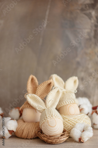 Easter eggs in crochet knitted hats with rabbit ears in nest. Easter celebration concept