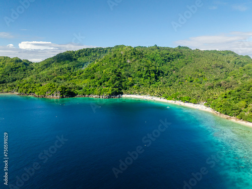Coastline with boats over white sand beach. Alad Island with blue sea. Romblon, Philippines.