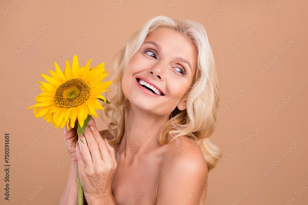 Photo of gorgeous cute adorable retired lady fresh sunflower smell gel balm lotion product empty space isolated on beige color background Photo of gorgeous cute adorable retired lady fresh sunflower smell gel balm lotion product empty space isolated on beige color background