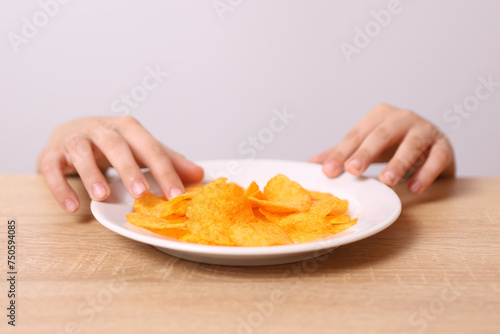 Children's hands are visible from under the table, trying to take potato chips from the table.