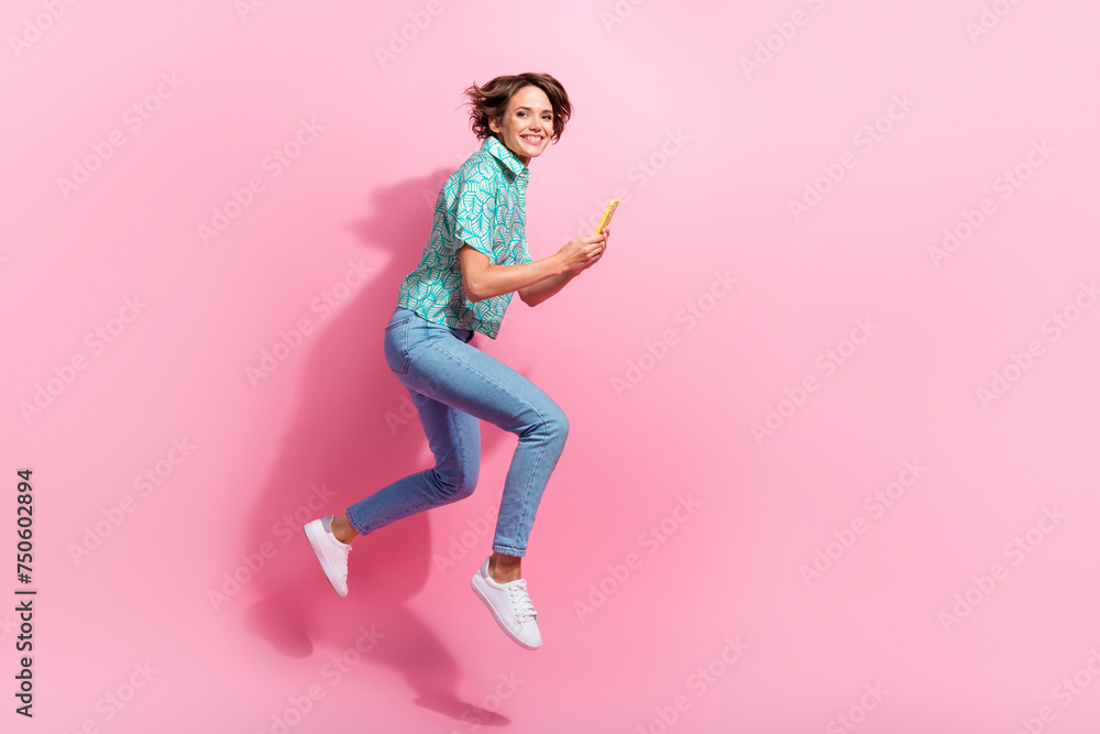Full length profile photo of excited person jump rush use smart phone empty space isolated on pink color background
