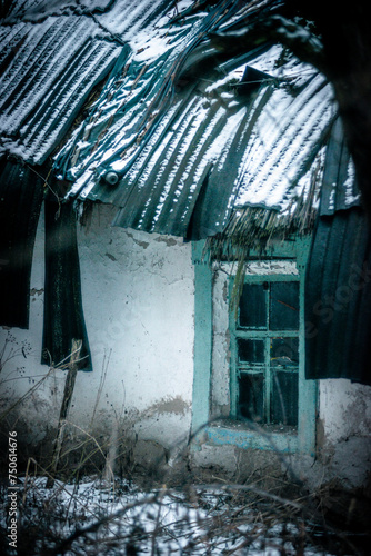 Abandoned house in the forest village at winter. Mystery landscape archittcture. Evening at village. Snow on the roof photo