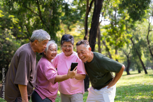 Group of happy Senior Retirement Using Smartphone and laughing outdoors at the park after a workout and spending time together, concepts about the elderly, seniority, and wellness aging