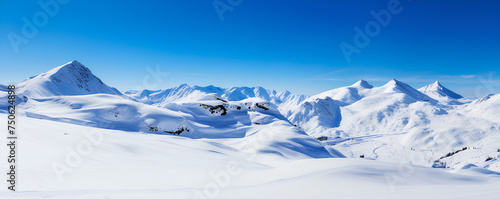 A solitary figure treks across snow-covered mountains under a clear blue sky