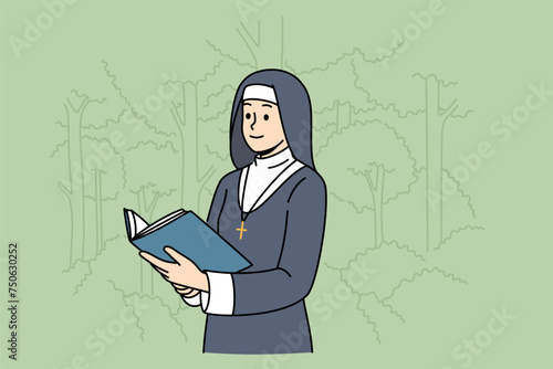 Woman nun with holy book stands in park among trees, dressed in cassock for religious service in temple. Nun studies sacred scriptures and prayers during breaks between prayer services in cathedral