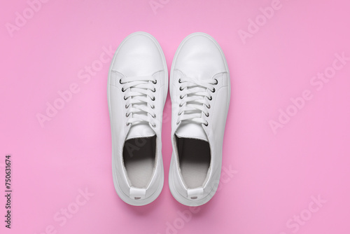 Pair of stylish white sneakers on pink background, top view